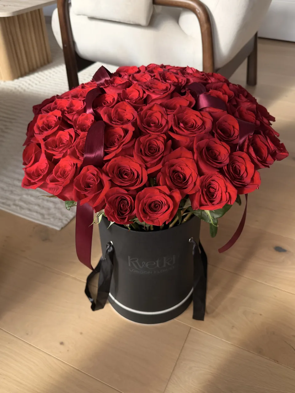 Red roses with burgundy ribbon in a black KVETKI hatbox