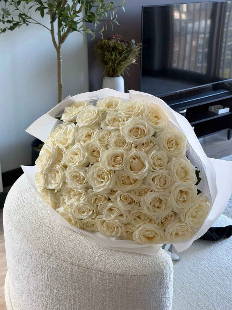 A generous round bouquet of creamy white roses in layered white wrapping