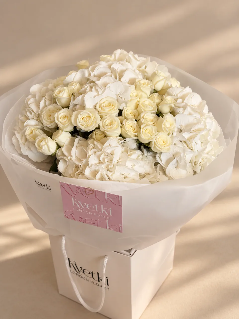 White rose and white hydrangea bouquet in white wrapping with a KVETKI gift bag